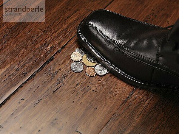 Finding money concept of a man shoe stepping on change coins on the floor