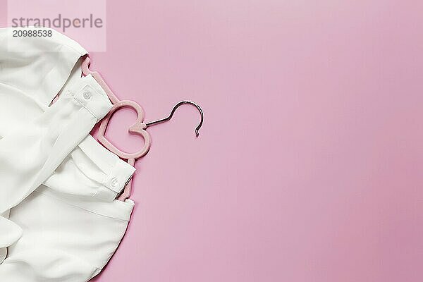 Black Friday  clothing industry concept on pink background flat lay with pink clothes hanger and white blouse dress with heart shape on hanger