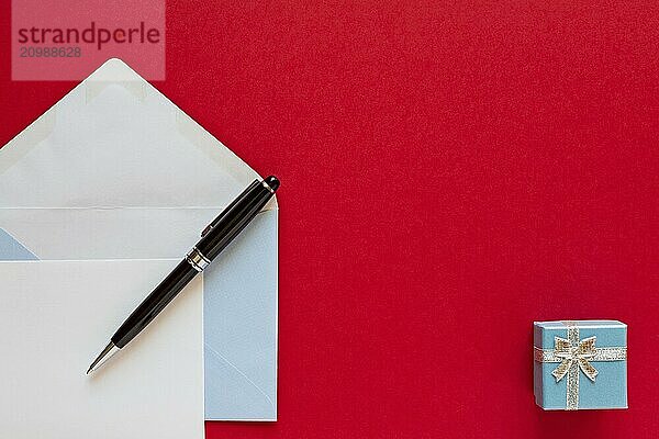 Christmas letter and pen over a red background with present