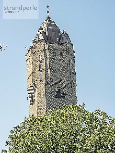 A historic tower rises above green trees in a sunny blue sky  trelleborg  sweden  baltic sea  scandinavia