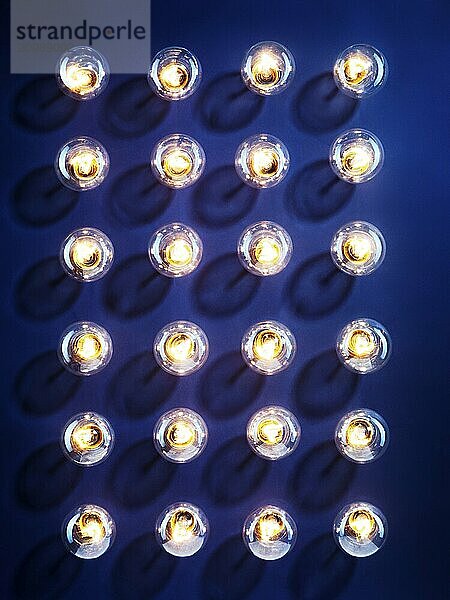 A group of illuminated incandescent light bulbs shining isolated on blue background