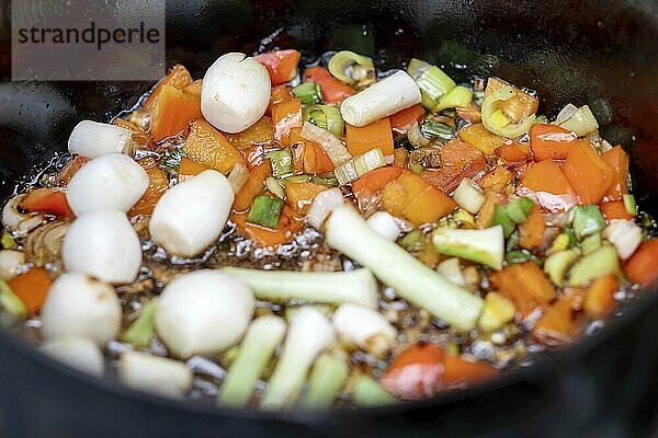 Sautéing vegetables in a pan against a black background  close-up