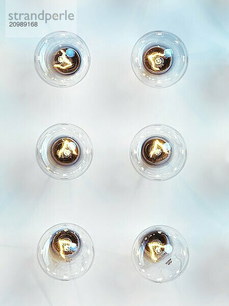 Six incandescent tungsten light bulbs on light blue background