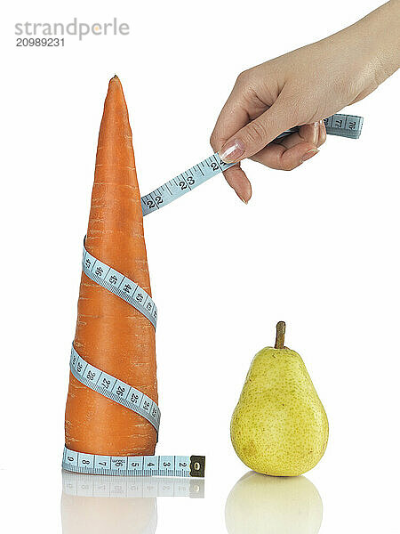 Woman with a tape measure around a carrot. Isolated on white. Healthy eating and weight loss concept