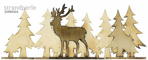 Stag figure sawn out of wood with dark edges and wooden fir trees cut out on white