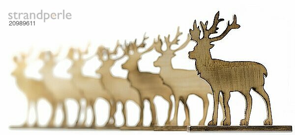 Deer figure sawn out of wood with dark edges and wooden fir trees cut out on white