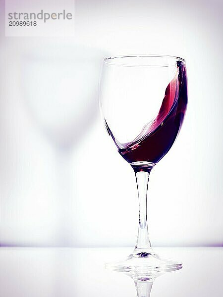 Red wine in a glass artistic photo isolated on bright white pink background