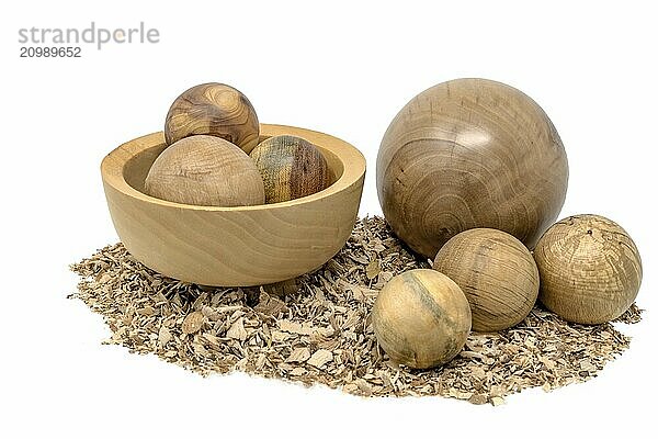 Hand-turned wooden baubles in a bowl decorated with sawdust on a white background