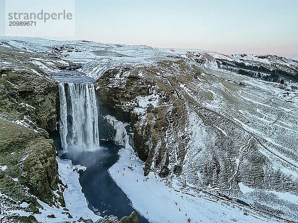 Drone aerial view of frozen Skogafoss waterfall filled with snow in winter in Iceland