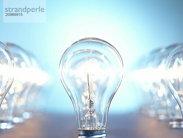 Closeup of lit up incandescent light bulbs on bright blue background. Power consumption concept