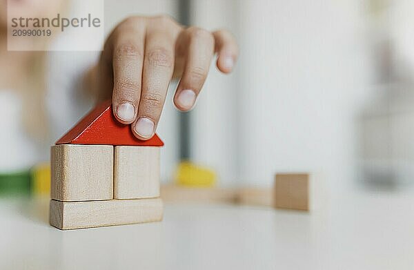 Little child girl of preschooler age playing wooden building blocks at home or kindergarten. Kid is stacking tower from colourful toys on table. Kids Play Room. Development  construction concept