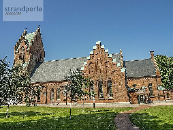 Wide angle photo of a brick church with tower and square surrounded by trees  trelleborg  sweden  baltic sea  scandinavia