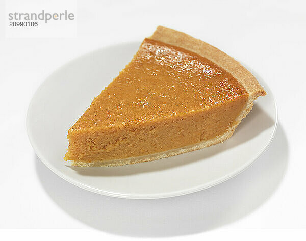 Piece of a pumpkin pie on a saucer isolated on white background