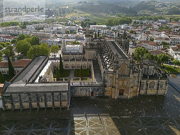 Aerial view of a historic monastery in Gothic architecture  surrounded by buildings and nature in a green landscape  aerial view  monastery  Mosteiro de Santa Maria da Vitória  'unfinished chapels'  UNESCO World Heritage Site  Batalha  Leiria  Estremadura  Portugal  Europe