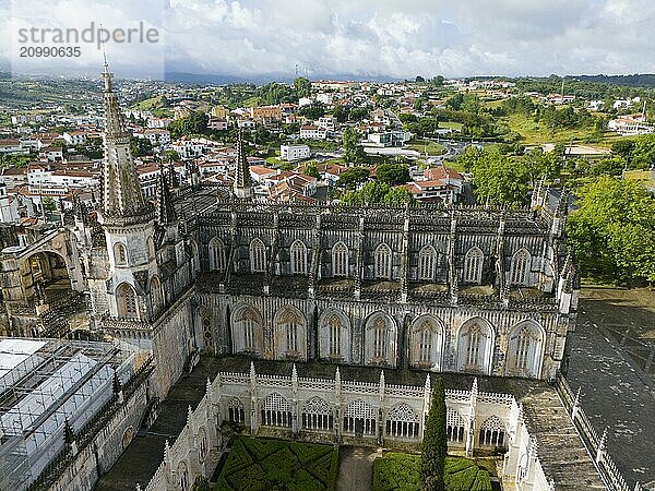 Aerial view of a Gothic cathedral with a magnificent tower and windows  an inner courtyard is visible and the surrounding area consists of a green landscape and town  aerial view  monastery  Mosteiro de Santa Maria da Vitória  'unfinished chapels'  UNESCO World Heritage Site  Batalha  Leiria  Estremadura  Portugal  Europe