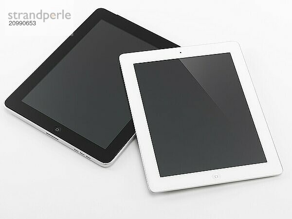 White Apple iPad 2 and black iPad tablet computers. Isolated on white background