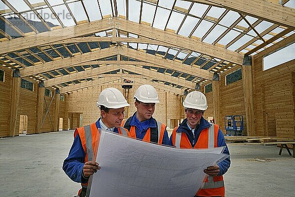 Three builders discuss the plan for a major construction job