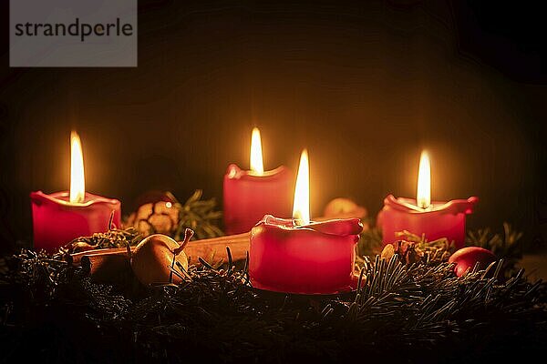 Decorated Advent wreath made of fir branches with burning red candles against a black background