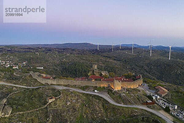 Drone aerial view of Sortelha historic village at sunset with lights on the castle eolic wind turbines and nature landscape  in Portugal