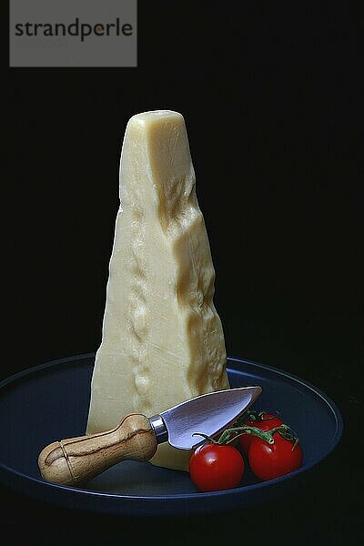 A piece of Parmesan cheese with cheese knife and tomatoes  Italy  Europe