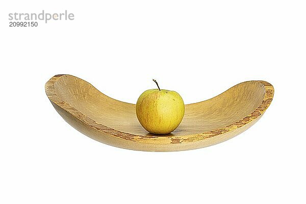 Side view of a flat wooden bowl with an apple in the centre  cropped on white