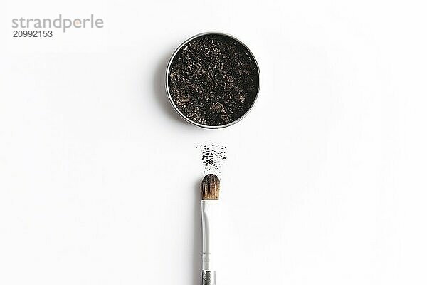 Dark brown face shadow in container and eye shadow or make-up brush. Makeup concept flat lay on white background