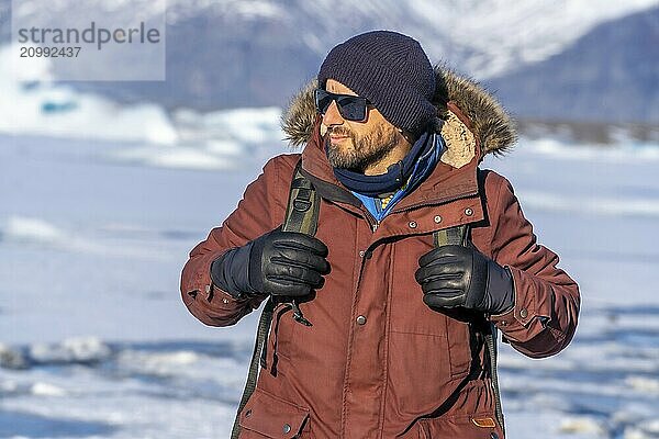 Portrait of a hiker walking on the frozen lake of Jokulsarlon glacier in Iceland