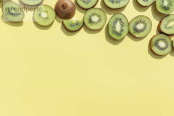 Slices and cuts of kiwi fruit on yellow background. Healthy eating  travel or vacation concept