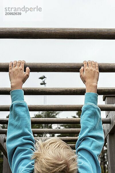 Gothenburg  Sweden  May 09 2021: Kid hanging from the hands off a wooden pole  Europe