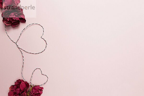 Valentine card. Heart shapes. Red white string or rope. Roses. Pink background.