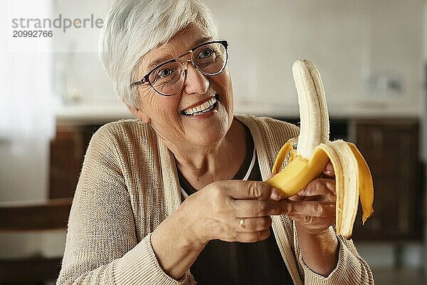 Older woman with grey hair and glasses smiles while peeling a banana  AI generated  AI generated