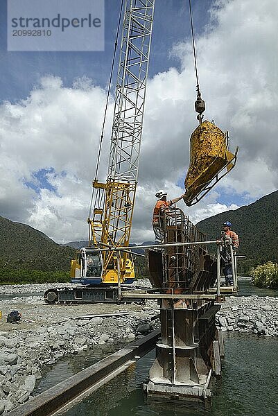 Builders construct a concrete bridge over a small river in Westland  New Zealand  Oceania