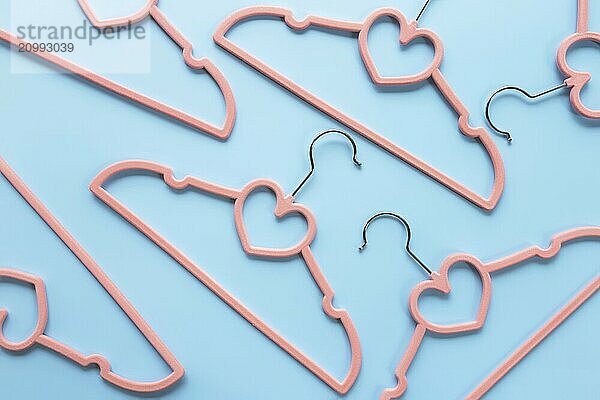 Black Friday or clothing industry concept on blue background flat lay with randomly scattered pink clothes hangers pattern