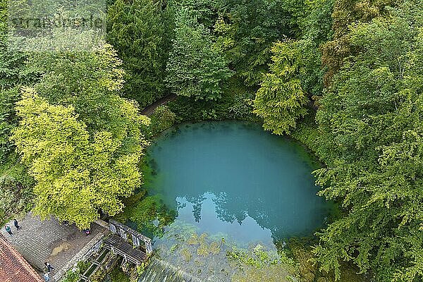 Blautopf Blaubeuren  source of the River Blau in a landscape with forest. Karst spring  geotope and geopoint of the UNESCO Swabian Alb Geopark  tourist attraction. The popular excursion destination is now being thoroughly renovated and will therefore be closed to visitors until the end of 2028. Drone photo. Blaubeuren  Baden-Württemberg  Germany  Europe