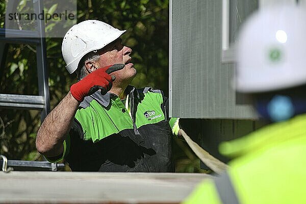 GREYMOUTH  NEW ZEALAND  OCTOBER 21  2020: A crane operator works on lifting a small building from a truck onto its pilings