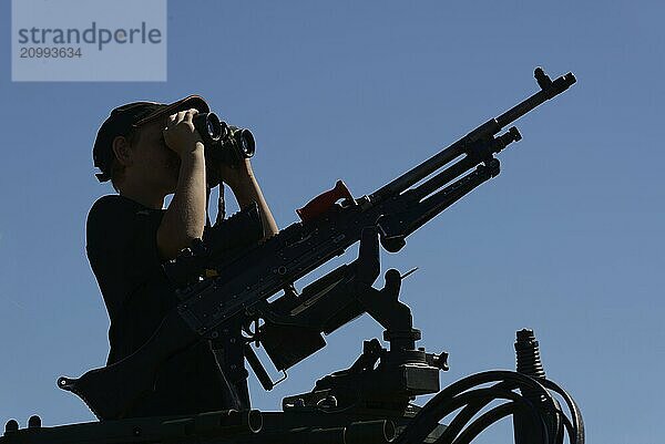 GREYMOUTH  NEW ZEALAND  NOVEMBER 18  2017: An unidentified schoolboy scans the horizon with binoculars at an open day run by the New Zealand armed forces. The machine gun is a Mag 58 GM