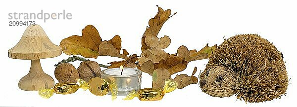 Christmas decoration with autumn leaves  candle  wooden mushroom and straw hedgehog against a white background