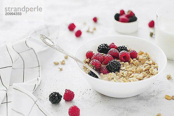 Morning healthy breakfast  white bowl full with granola  muesli  raspberry  blackberry on gray concrete table. Healthy eating  eco  bio food concept. Fresh tasty meal on grey background. Quality photo