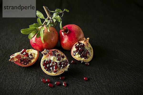 Pomegranate fruits and seeds over a textured black background