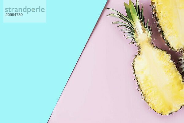 Flat lay with cut halves of fresh pineapple on a pastel pink and blue background. Ingredient for Pina Colada. Exotic fruit.