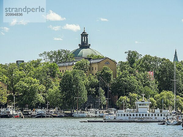 Church with green roof  boats and trees surrounded by summer sky  stockholm  baltic sea  sweden  scandinavia