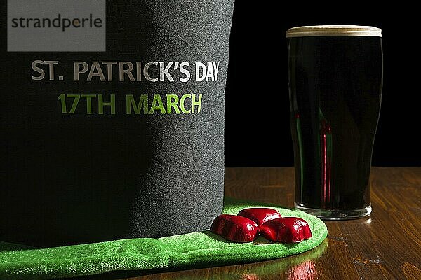 Closeup of St Patrick day with a pint of black beer and hat over a table and black background