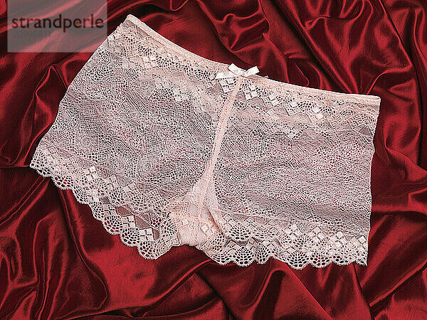 Pink lacy underwear on red shiny silky fabric