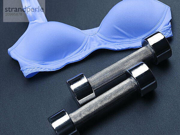 Shiny chromed exercise weights and blue sports bra