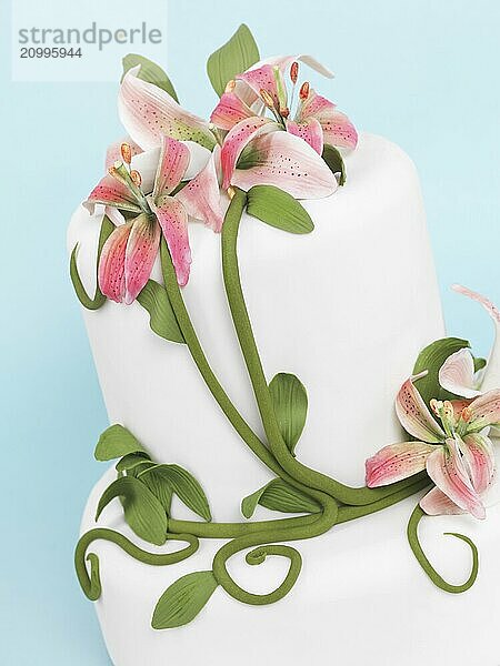 Fancy cake decorated with lilies isolated on blue background