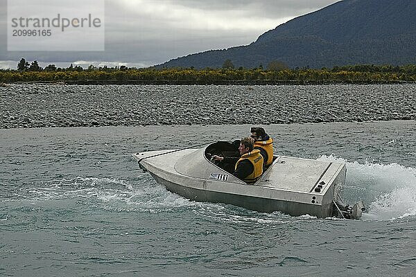 TARAMAKAU RIVER  WEST COAST  NEW ZEALAND  SEPTEMBER 3  2019: Two young men power their jetboat down the Taramakau River