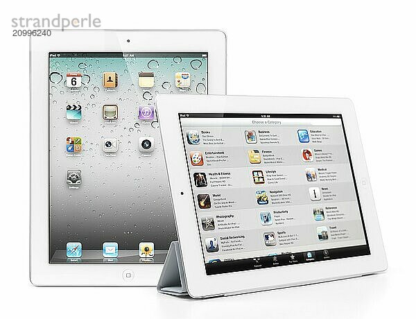 Two Apple iPad 2 tablet computers desktop and app store on their displays. Isolated on white background