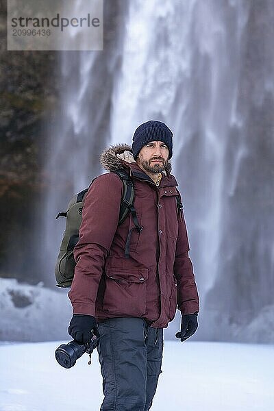 Portrait of a photographer in winter at Seljalandsfoss waterfall with snow in Iceland