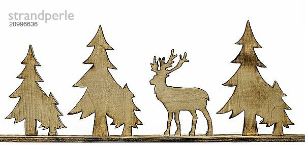 Deer figure sawn out of wood with dark edges and wooden fir trees cut out on white