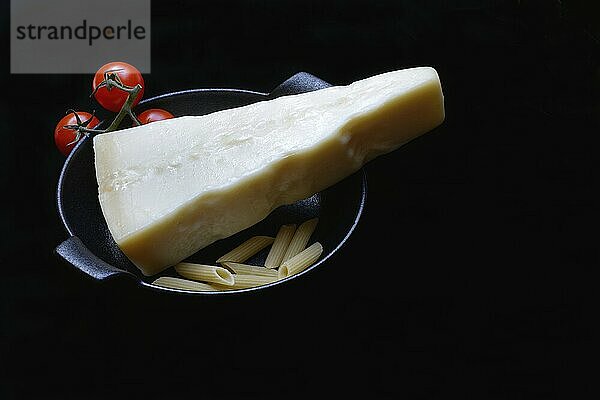 A piece of Parmesan cheese with tomatoes and pasta  Italy  Europe